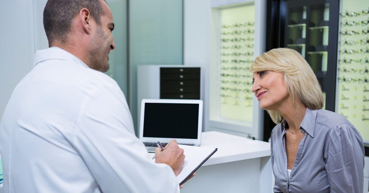 Male ophthalmologist talking to female patient in clinic